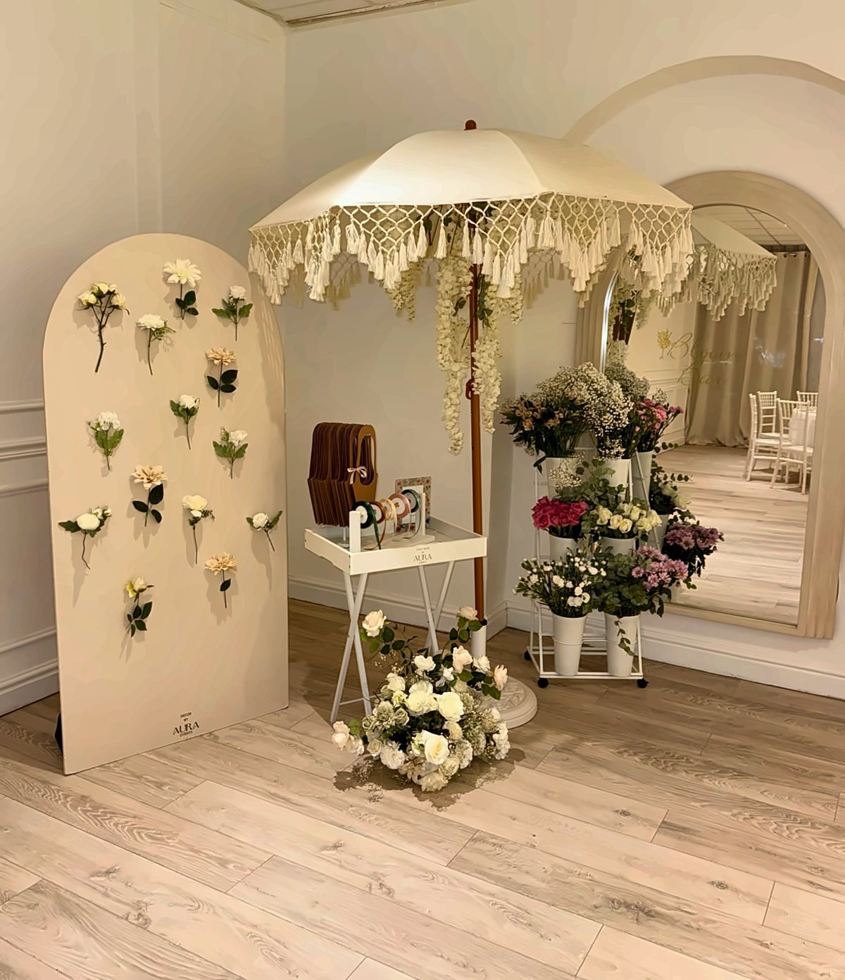 A flower bar with a fringed parasol, buckets of fresh flowers and a wall of blooms