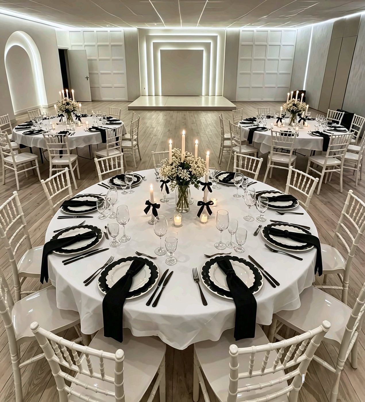 Round tables laid in black and white with candles and gypsophila, white chiavari chairs