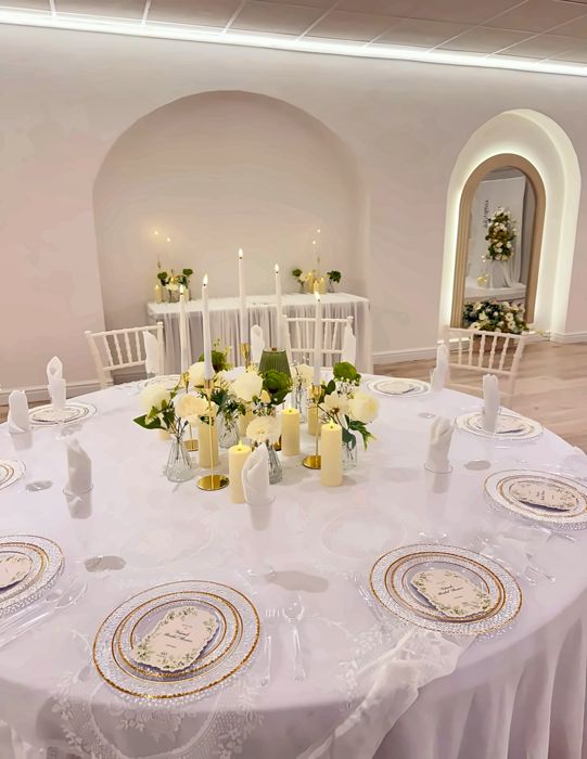 A round table laid with lace, gold-rimmed plates and candles at The XL Suite